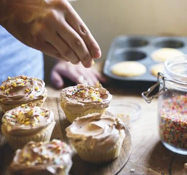 Hand adding sprinkles to chocolate cupcake food photography recipe idea Stock Photos