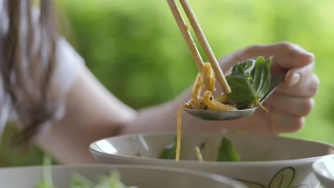 Hand adding Thai basil leaves to noodle spoon as a seasoning for eat. Video stock 156604152