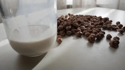 Hand Adding Tiger Nuts to Glass of Milk on Sunlit Table in Preparation Process Stock Footage 336477654