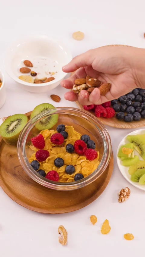 Hand Adding Walnuts and Almonds to a Healthy Breakfast Cereal Bowl Stock Footage 337689620