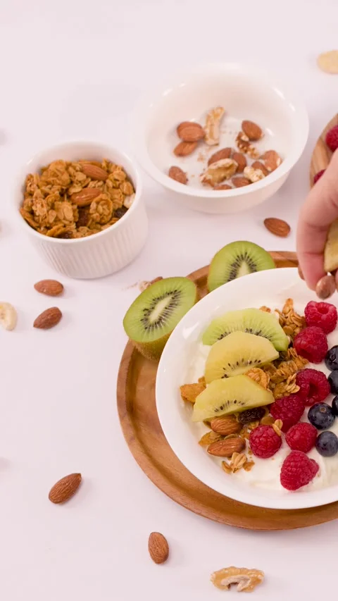 Hand Adding Whole Almonds to a Fresh Greek Yogurt Breakfast Bowl Stock Footage 337917888