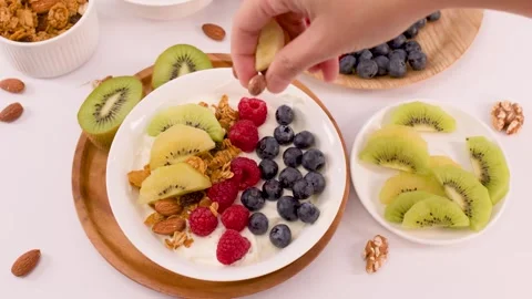 Hand Adding Whole Almonds to a Greek Yogurt Fruit Bowl Stock Footage 337917838