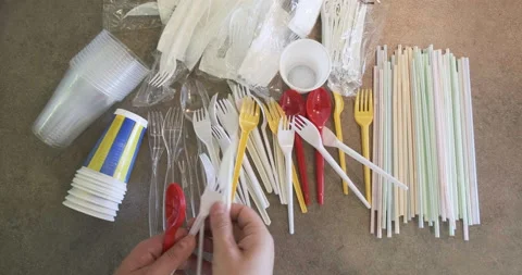 Hand adds plastic cutlery on table with single use plastic items banned in EU. Stock Footage 156902885