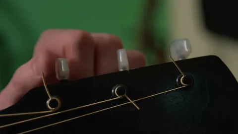 A hand adjust the knobs on a guitar while tuning the guitar 動画素材 131496444