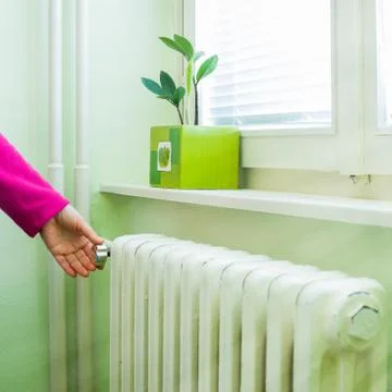 Hand adjust the volume of heating valve on the radiator Stock Photos
