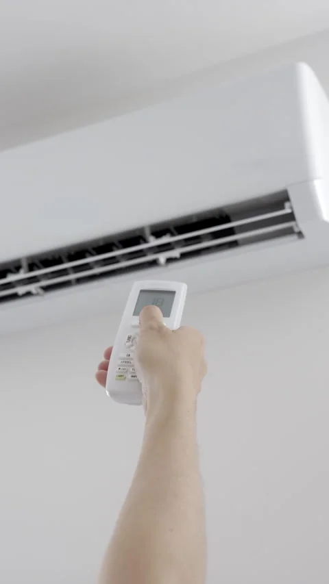 Hand adjusting air conditioner remote control at home Stock Footage 336608102
