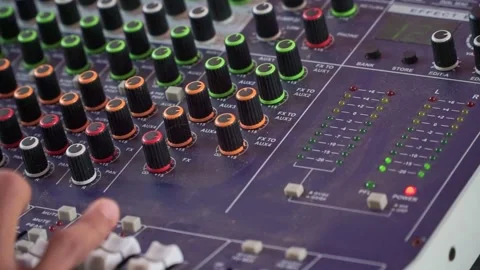 Hand adjusting audio mixer knobs, sound engineering console with colorful Stock Footage 344012203