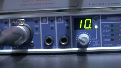 Hand adjusting the buttons on a functioning audio amplifier in a sound recording Video stock 70822728