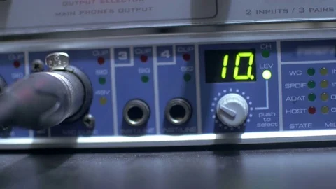 Hand adjusting the buttons on a functioning audio amplifier in a sound recording 動画素材 70830121