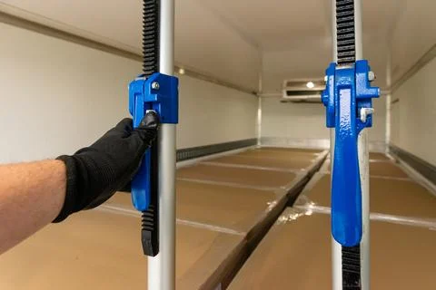 Hand adjusting cargo stabilizer bar in commercial vehicle Stock-Fotos