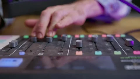 Hand adjusting controls on a podcast console, turning knobs and pushing Video stock 297347484