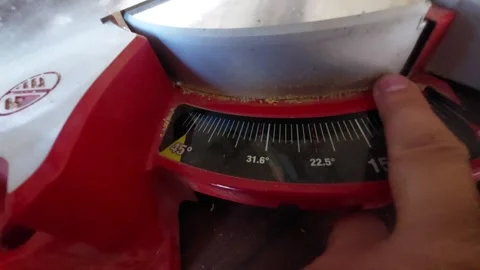Hand adjusting the cutting angle degree scale on a red miter saw close up Vídeo Stock 335403444