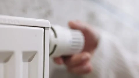 A hand adjusting the heating radiator as cold weather sets in 库存影片 295883432