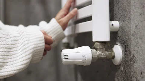 A hand adjusting the heating radiator as cold weather sets in 库存影片 295883718