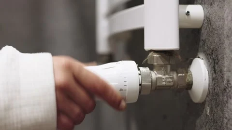 A hand adjusting the heating radiator as cold weather sets in 库存影片 295883771