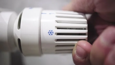 A hand adjusting the heating radiator as cold weather sets in 库存影片 295885410