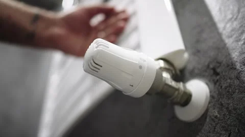 A hand adjusting the heating radiator as cold weather sets in 库存影片 295885525
