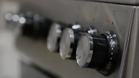A hand adjusting knobs on a metallic stove panel. Shallow depth of field. Video stock 265892191