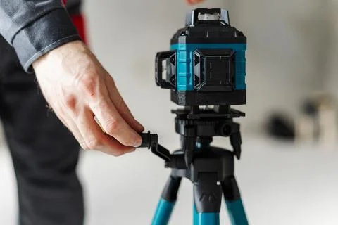 Hand Adjusting Laser Level Mount On Tripod Using Quick Release Lever. Stock Photos