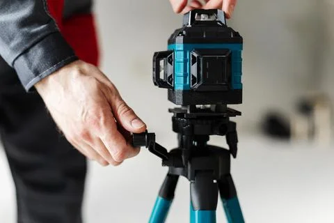 Hand Adjusting Laser Level Mount On Tripod Using Quick Release Lever. Stock Photos