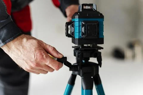 Hand Adjusting Laser Level Mount On Tripod Using Quick Release Lever. Stock Photos