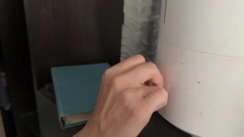 Hand adjusting mode on air humidifier, setting indoor moisture level on modern Stock Footage 337119866