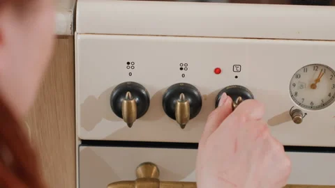 Hand adjusting oven control knob on white enamel stove, showing cooking Stock-Footage 343677381