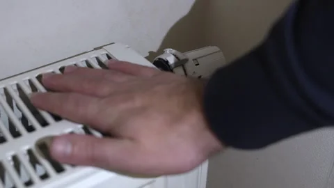 Hand adjusting a radiator thermostat to regulate heating, symbolizing energy Stock Footage 322135750