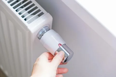 Hand adjusting radiator valve to control room heating temperature Stock Photos