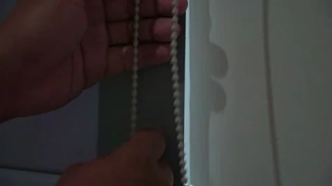 Hand adjusting a roller curtain with a pull chain. Modern interior, Stock Footage 339122272