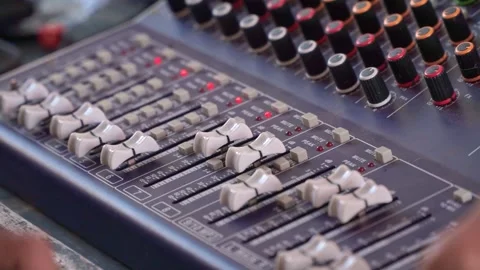 Hand adjusting sound console dials, mixing board with LED levels, Stock Footage 344011589