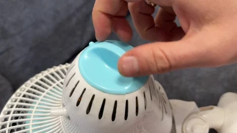 Hand adjusting speed control knob on portable fan, personal cooling appliance Stockbeeldmateriaal 337121294