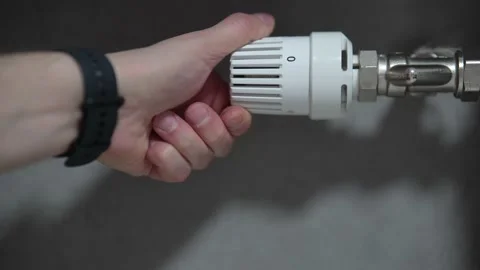 Hand adjusting temperature on heating radiator thermostat, saving energy by Stock Footage 217529346