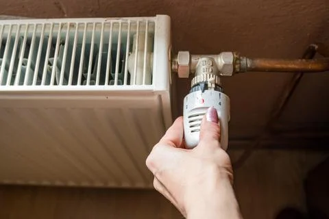 Hand adjusting temperature on heating radiator thermostat, Economy concept Stock Photos