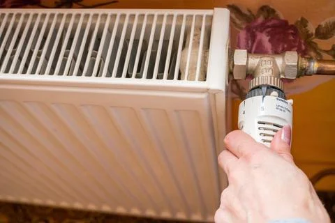 Hand adjusting temperature on heating radiator thermostat, Economy concept Stock Photos