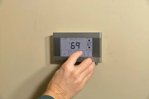 Hand adjusting temperature on thermostat Stock Photos