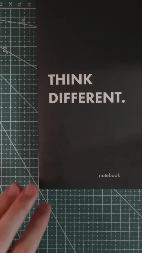 Hand adjusting Think Different notebook on green cutting mat Stock Footage 341246091
