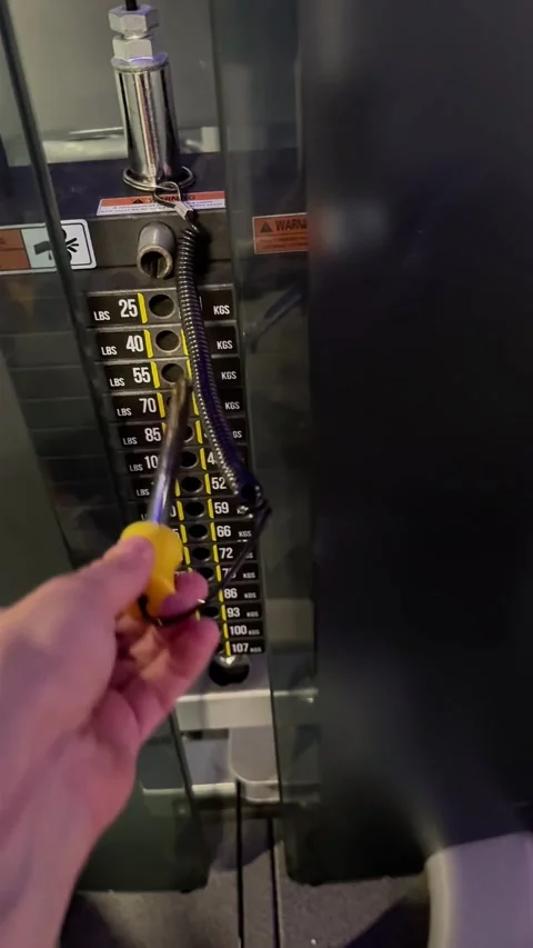 Hand Adjusting Weight Stack Pin on a Gym Exercise Machine in Fitness Club Stock Footage 347587775