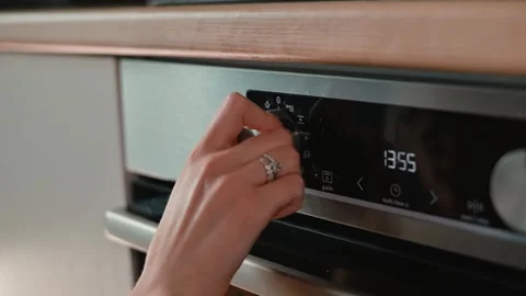 A hand adjusts the dial on a modern kitchen oven to set the cooking temperature Video stock 339094669
