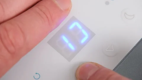 Hand adjusts temperature setting on a modern air conditioner control panel Stock Footage 336617090