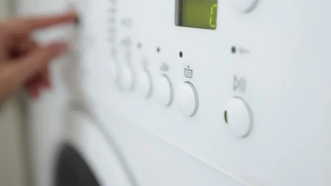Hand adjusts washing machine settings on control panel, turning dial and Stock Footage 334690194