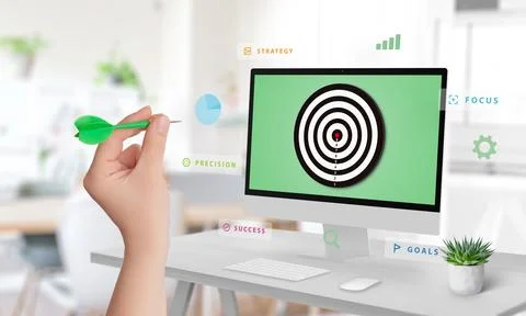 Hand aiming at a display with a target surrounded by floating words like goal Stock Photos