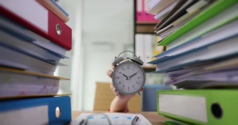 Hand with alarm clock from large stack of papers and folders on table Stock Footage 259614671