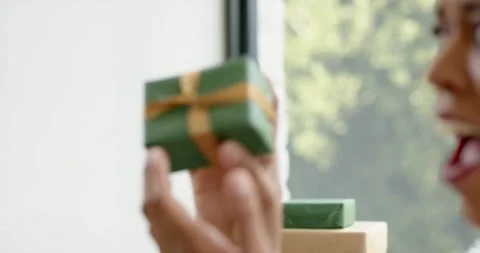 Hand appearing in frame is placing small green gift box onto larger package and Stock Footage 340980233