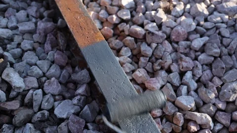 Hand applies coating to rusted steel flat bar on gravel ballast Stock Footage 337581853