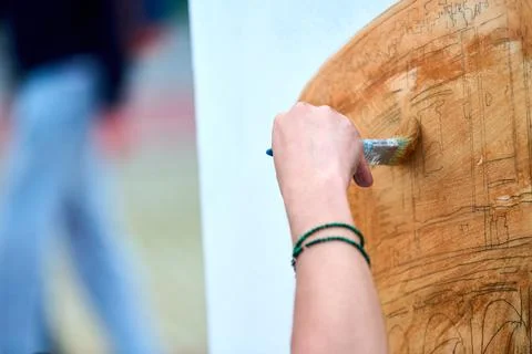 Hand applying brown paint to circular canvas sketch with brush in studio li.. Stock Photos