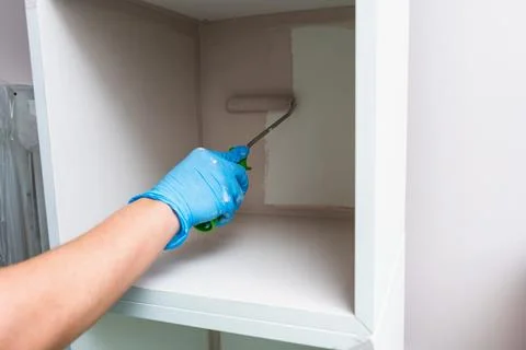 Hand Applying Fresh Paint Inside Cabinet With Roller Foto stock