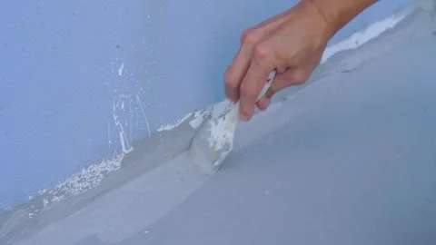 Hand applying gray sealant or paint with a brush along the edge of a blue w.. Video stock 331280494