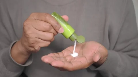 Hand applying green product from a small tube Stock Footage 342384688
