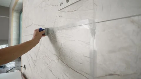 Hand applying grout between marble tiles with trowel Stock Footage 340335040